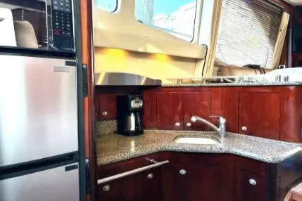 Salty Pause Yacht Photos Pics 2005 Sea Ray 420 Sedan Bridge kitchen with granite countertops, stainless steel appliances, and wood cabinetry.