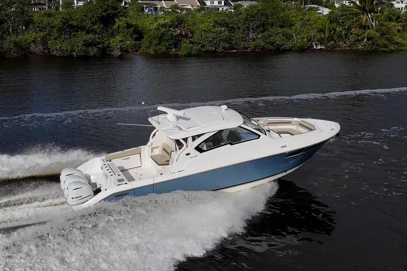  Yacht Photos Pics 2019 Pursuit DC 365 Dual Console boat cruising on a river with lush greenery.