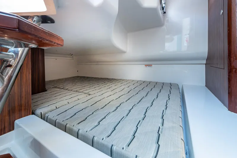  Yacht Photos Pics 2019 Pursuit DC 365 Dual Console cabin interior with striped bedding and wooden accents.