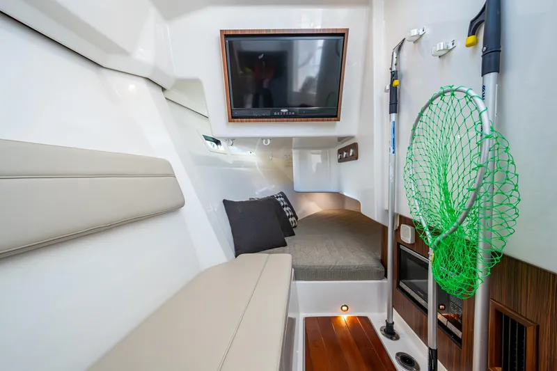  Yacht Photos Pics 2019 Pursuit DC 365 Dual Console cabin interior with seating, TV, and fishing gear.