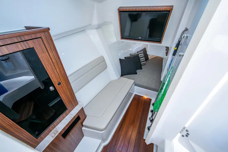  Yacht Photos Pics 2019 Pursuit DC 365 Dual Console cabin with seating, TV, and wooden accents.