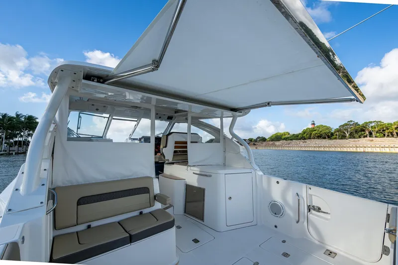  Yacht Photos Pics 2019 Pursuit DC 365 Dual Console boat interior with seating and canopy, near waterfront.