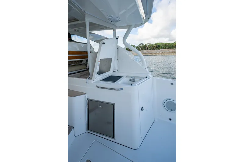  Yacht Photos Pics 2019 Pursuit DC 365 Dual Console boat interior with open storage compartment by the water.