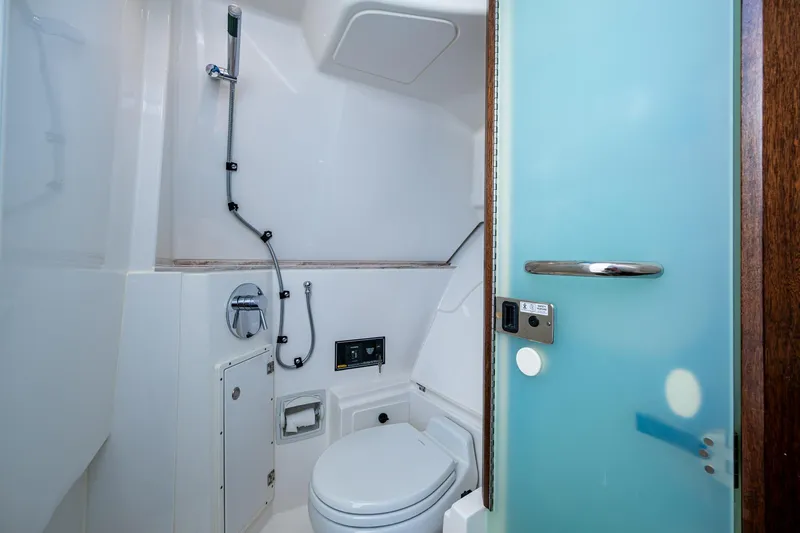  Yacht Photos Pics 2019 Pursuit DC 365 Dual Console boat bathroom with modern fixtures and frosted glass door.