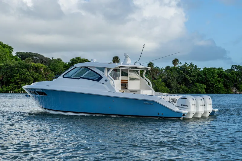  Yacht Photos Pics 2019 Pursuit DC 365 Dual Console boat on water, surrounded by lush greenery.