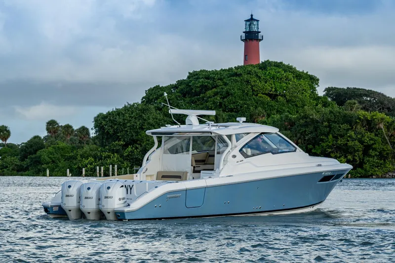  Yacht Photos Pics 2019 Pursuit DC 365 Dual Console boat cruising near a lighthouse and lush greenery.