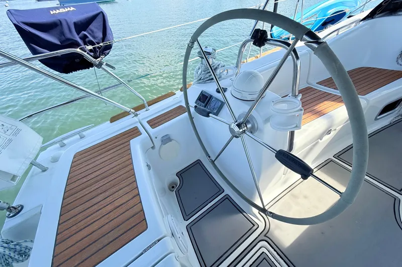 Sunniva Yacht Photos Pics Steering wheel of 2007 Beneteau Oceanis 46 sailboat with teak deck, docked on water.