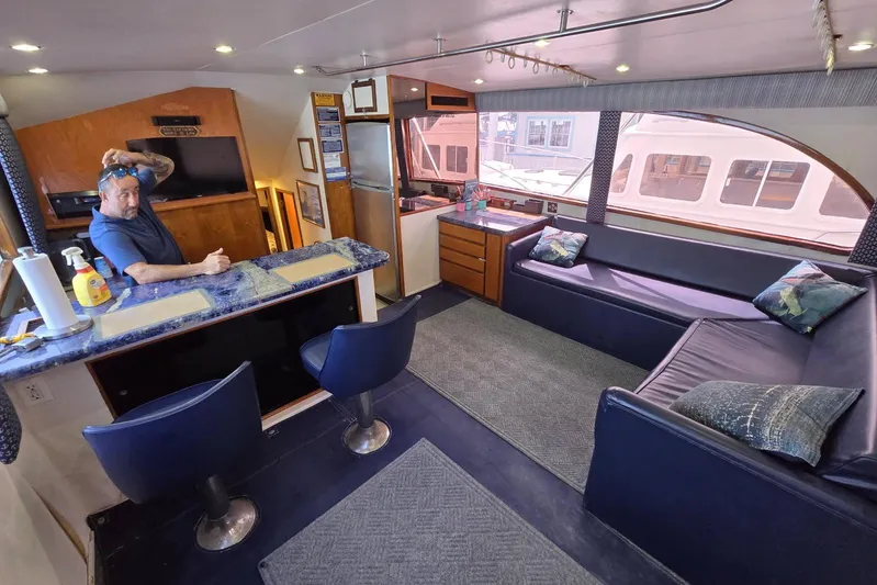  Yacht Photos Pics Interior of 1988 Topaz 44 Flybridge yacht with bar, seating, and man adjusting sunglasses.