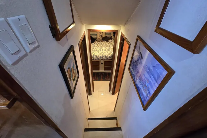  Yacht Photos Pics Narrow hallway in 1988 Topaz 44 Flybridge yacht with framed artwork and bedroom view.