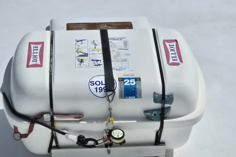  Yacht Photos Pics Life raft on 1988 Topaz 44 Flybridge boat, secured with straps and labeled "Elliot."