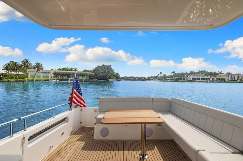 Mjm 42 For Sale Yacht Photos Pics 2024 MJM 42 yacht deck with seating, table, and American flag, overlooking serene waterfront homes.