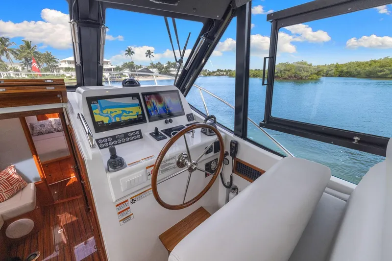 Mjm 42 For Sale Yacht Photos Pics 2024 MJM 42 yacht helm with navigation screens, overlooking serene waterway and lush greenery.