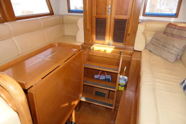 Peregrine Yacht Photos Pics Interior of 2002 Tayana 460 Vancouver Pilothouse with wooden table and beige seating.