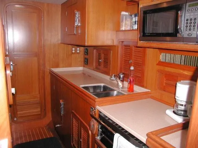Peregrine Yacht Photos Pics Interior of 2002 Tayana 460 Vancouver Pilothouse yacht kitchen with wood cabinetry and appliances.