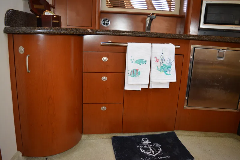 Knot On Call Yacht Photos Pics 2007 Sea Ray 44 Sundancer kitchen with wooden cabinets, towels, and stainless steel appliances.