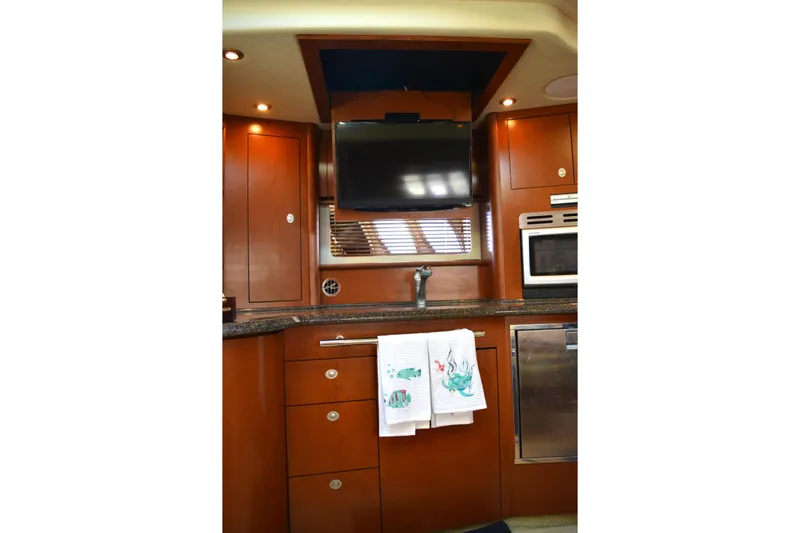 Knot On Call Yacht Photos Pics 2007 Sea Ray 44 Sundancer interior kitchen with wood cabinets, TV, and appliances.