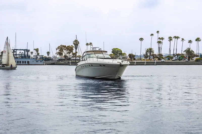  Yacht Photos Pics Sea Ray 510 Sundancer 2000 yacht cruising in a marina with palm trees in the background.