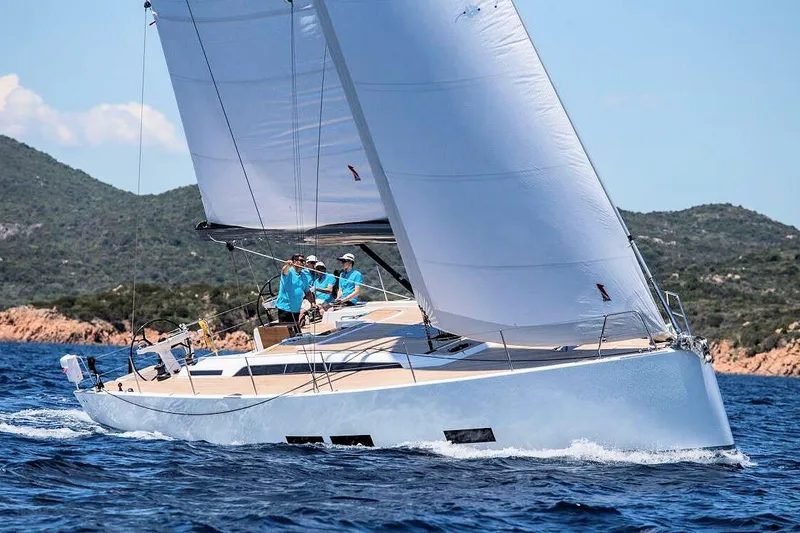 Nausicaä Yacht Photos Pics 2019 Solaris Yachts 55 sailing near rocky coastline under clear skies.