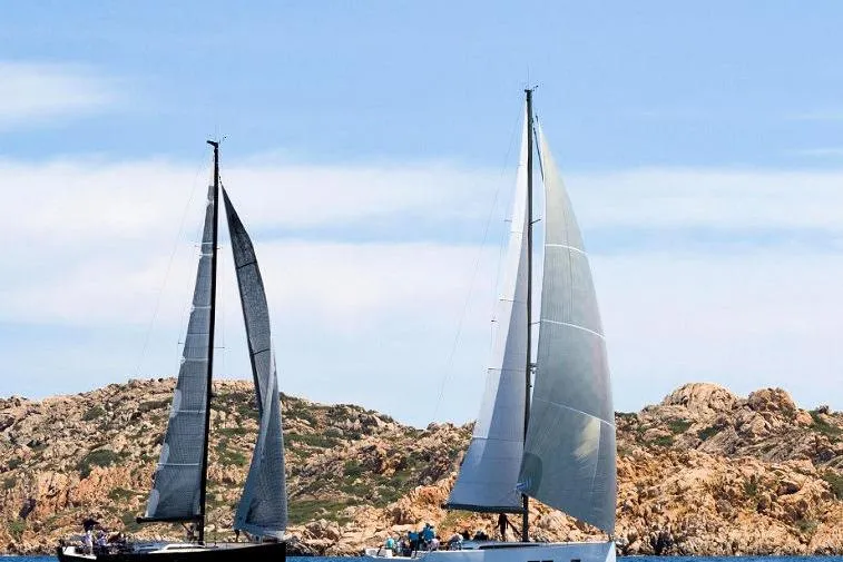 Nausicaä Yacht Photos Pics 2019 Solaris Yachts 55 sailing near rocky coastline under clear blue sky.