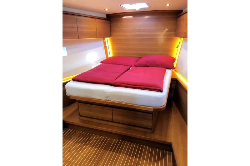 Nausicaä Yacht Photos Pics Luxurious cabin interior of 2019 Solaris Yachts 55 with wooden finish and red bedding.