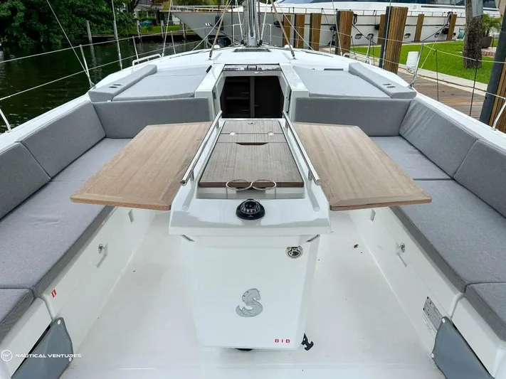  Yacht Photos Pics 2024 Beneteau Oceanis 51.1 yacht cockpit with wooden table and cushioned seating.