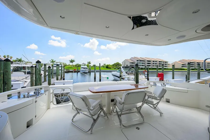 Vol Aboard Yacht Photos Pics Luxurious 2005 Marquis 65 MY yacht deck with seating, docked at a marina under a clear blue sky.