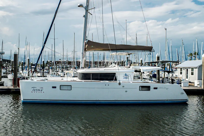  Yacht Photos Pics 2012 Lagoon 450 F catamaran docked at marina, surrounded by sailboats under cloudy sky.