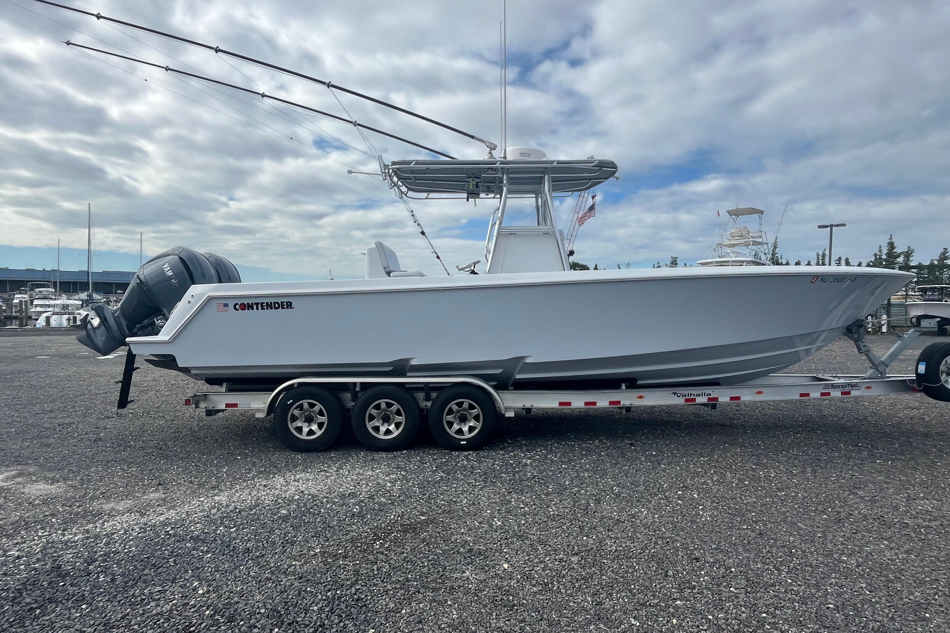 2022 Contender 32 ST boat on trailer, parked outdoors under cloudy sky.