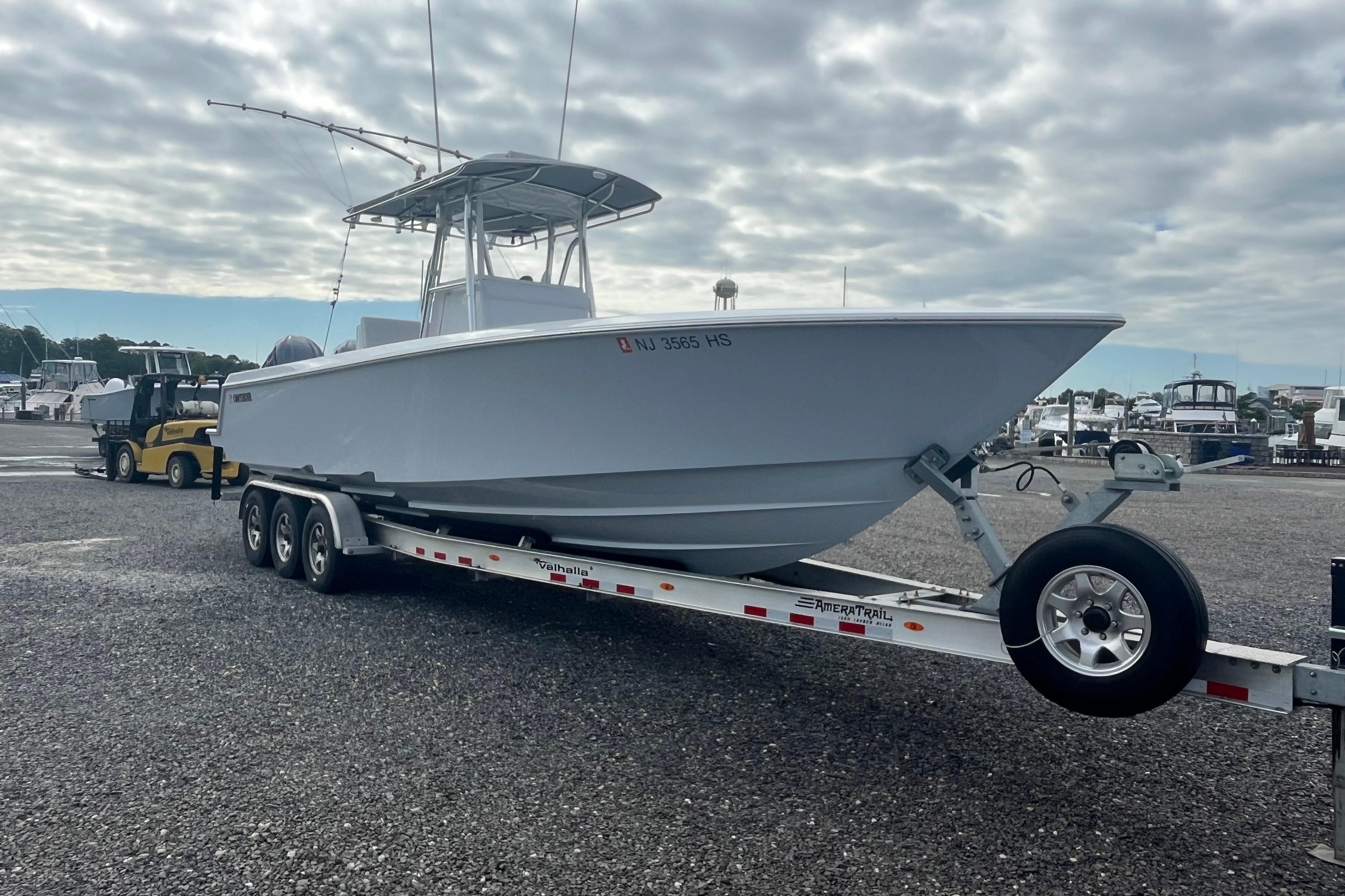 2022 Contender 32 ST boat on trailer, parked in marina under cloudy sky.