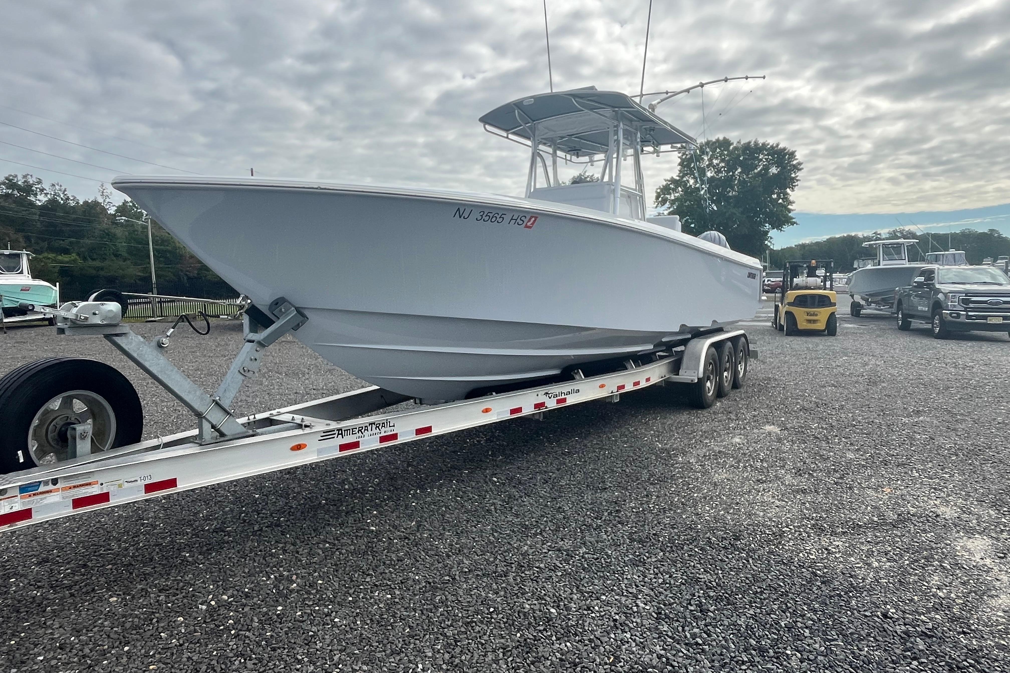 2022 Contender 32 ST boat on trailer, parked on gravel lot under cloudy sky.