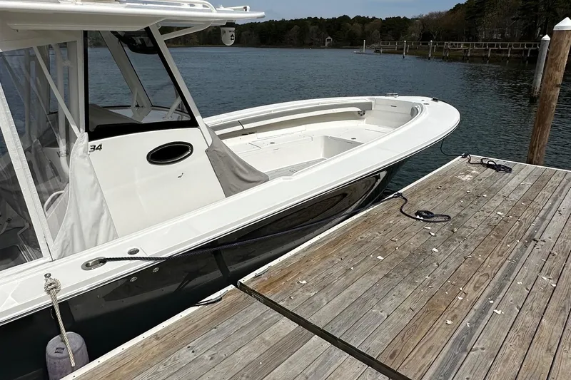 Grey Ghost Yacht Photos Pics 2023 Regulator 34 boat docked by a wooden pier on a calm lake.
