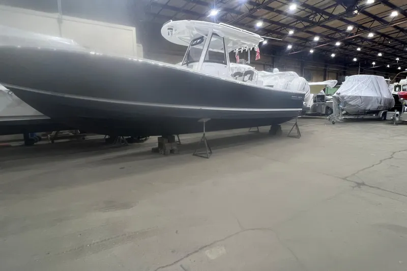 Grey Ghost Yacht Photos Pics 2023 Regulator 34 boat in a warehouse, elevated on stands, under bright lighting.