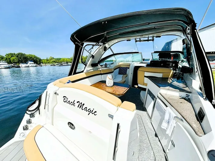  Yacht Photos Pics 2012 Rinker 310 Fiesta Vee boat interior, docked by a serene lake under clear blue skies.