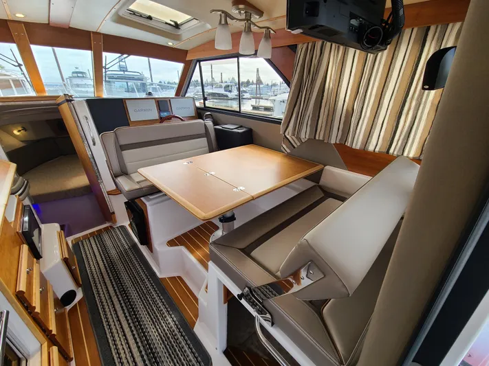  Yacht Photos Pics 2023 Cutwater C-30 Sedan NW Edition interior with dining area and striped curtains.