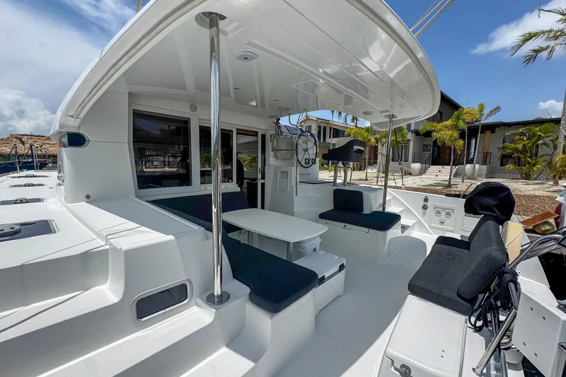 Wanderlust Yacht Photos Pics 2020 Lagoon 40 catamaran cockpit with seating, table, and helm, docked near tropical resort.