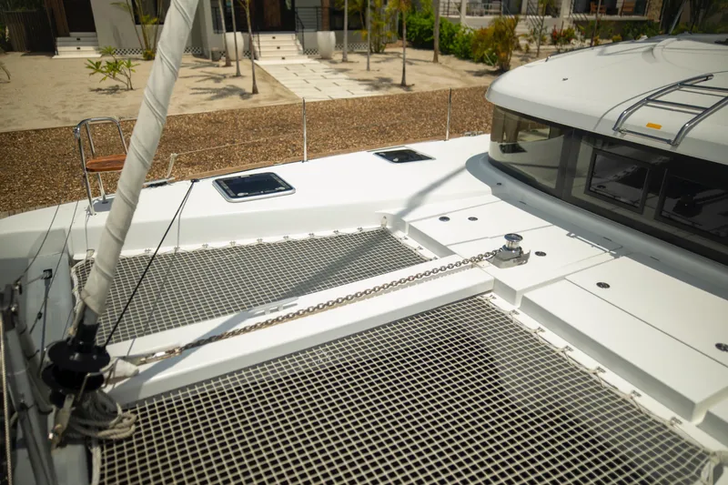 Wanderlust Yacht Photos Pics 2020 Lagoon 40 catamaran deck with netting and winch, docked near a beach.