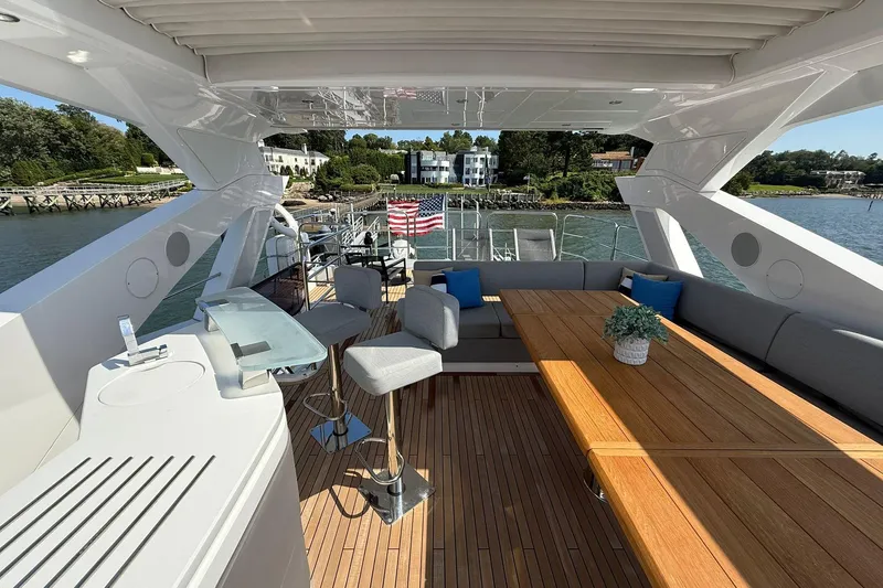  Yacht Photos Pics Luxurious 2021 Sunseeker 76 Yacht deck with seating, table, and scenic waterfront view.