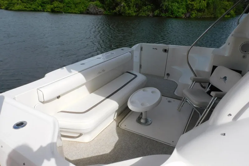 Full Deck Yacht Photos Pics 2008 Sea Ray 44 Sedan Bridge yacht deck with seating and table, near lush greenery.