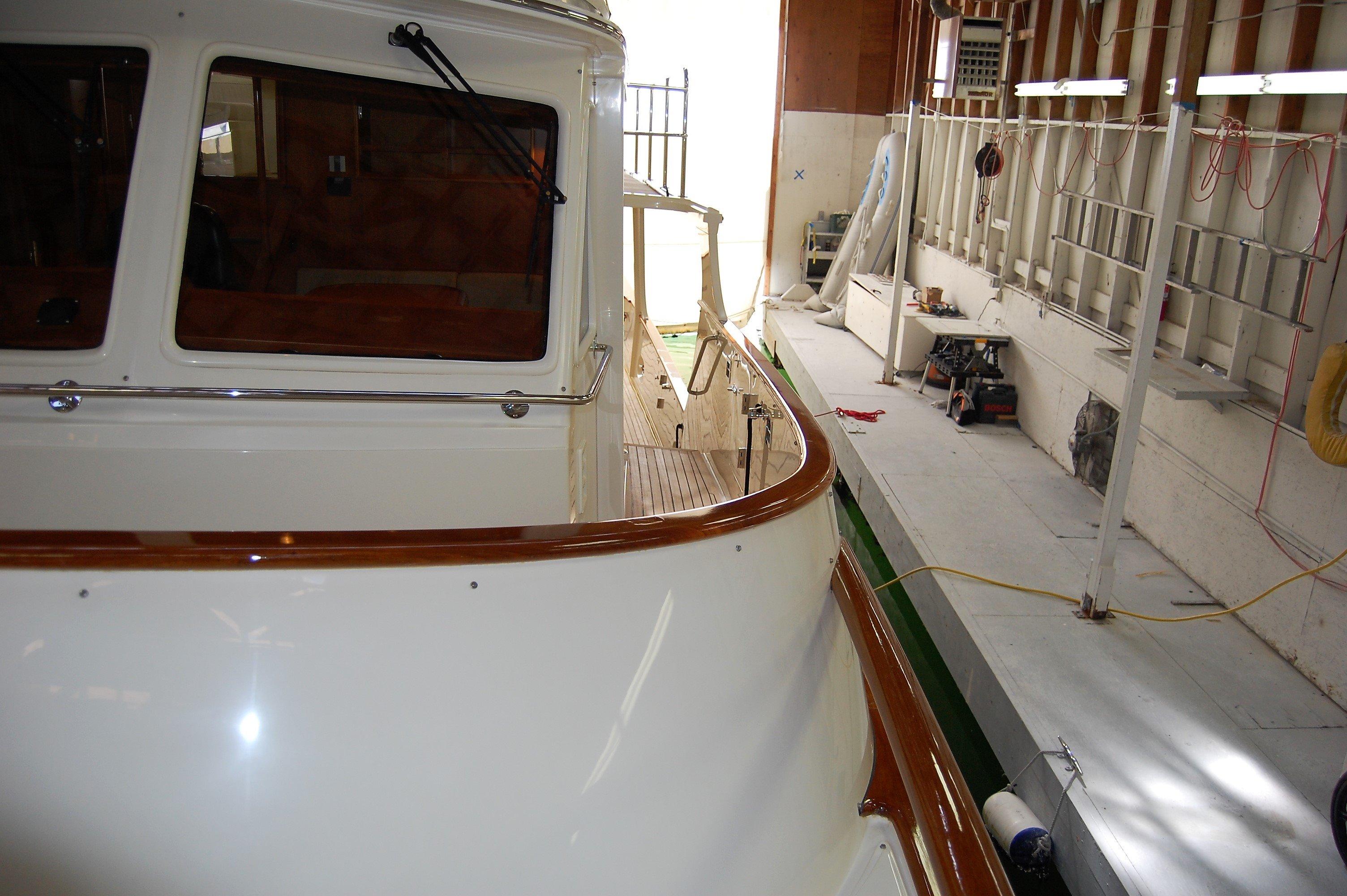 2009 Fleming Pilothouse yacht in a workshop, showcasing its sleek design and polished wood accents.