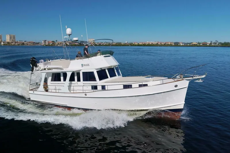 Magic Yacht Photos Pics Grand Banks 46 Europa 1996 yacht cruising on calm waters under clear blue skies.