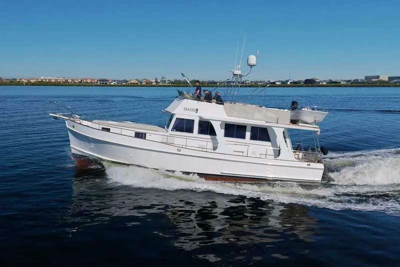 Magic Yacht Photos Pics Grand Banks 46 Europa 1996 yacht cruising on calm water under clear blue sky.