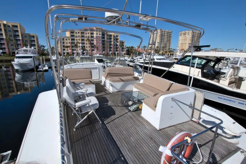 Magic Yacht Photos Pics 1996 Grand Banks 46 Europa yacht with spacious deck, docked in marina with cityscape background.