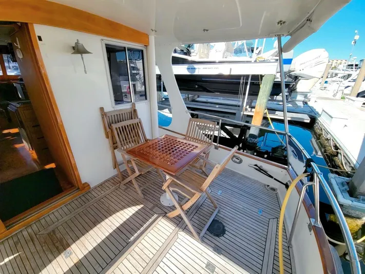Magic Yacht Photos Pics 1996 Grand Banks 46 Europa yacht deck with wooden chairs and table at marina.