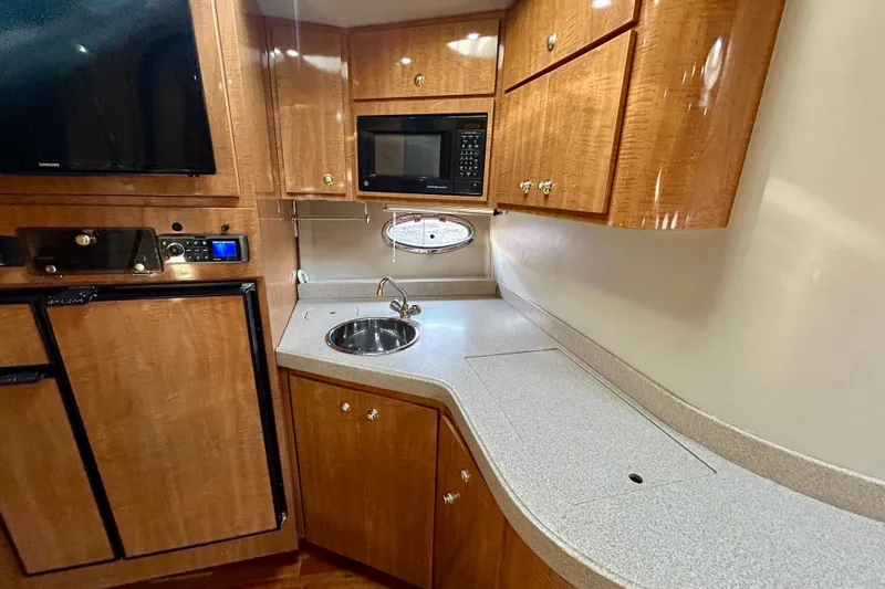 Done Deal Yacht Photos Pics 2002 Regal Commodore 3860 yacht kitchen with wood cabinets, sink, and microwave.