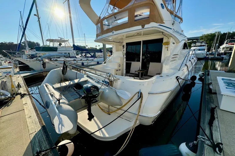 Lighten Up Yacht Photos Pics 2003 Sea Ray 400 Sedan Bridge yacht docked at marina with inflatable boat attached.