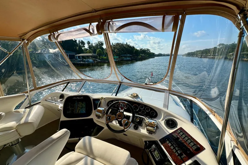 Lighten Up Yacht Photos Pics 2003 Sea Ray 400 Sedan Bridge helm with river view, featuring luxurious seating and navigation controls.