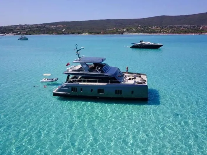 Double Happiness Yacht Photos Pics 2024 Sunreef 60 yacht anchored in clear turquoise waters, with scenic coastal backdrop.