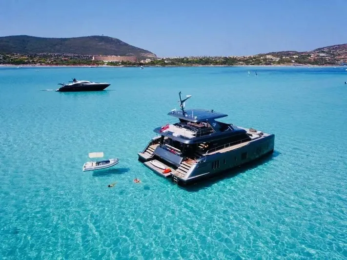 Double Happiness Yacht Photos Pics 2024 Sunreef 60 yacht anchored in clear turquoise waters, with scenic coastal backdrop.