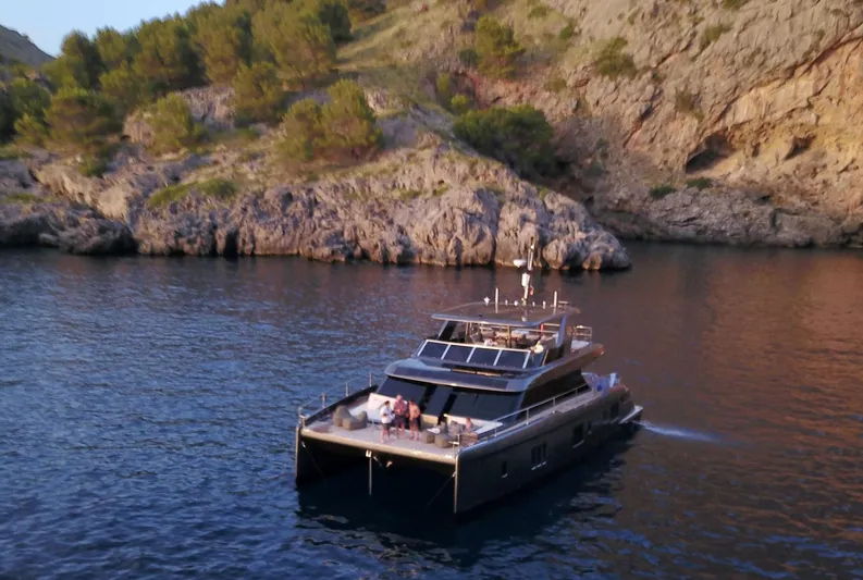 Double Happiness Yacht Photos Pics 2024 Sunreef 60 yacht cruising near rocky coastline at sunset.