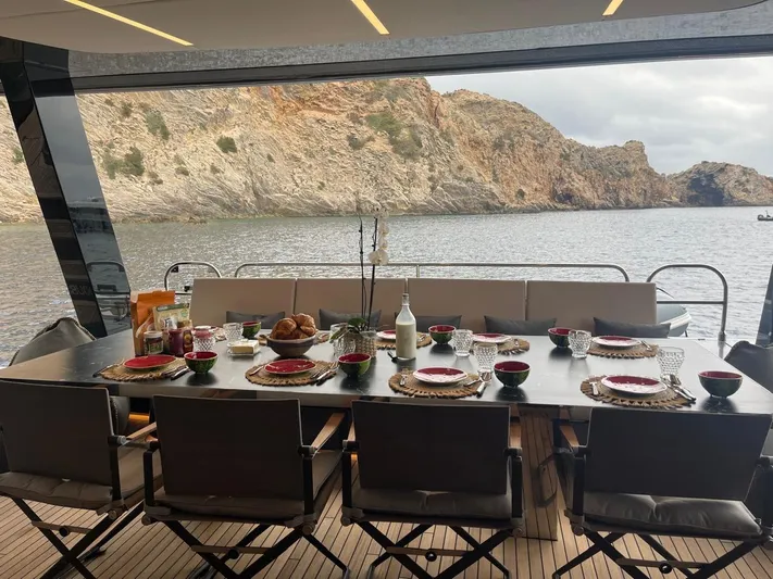 Double Happiness Yacht Photos Pics Luxurious dining setup on 2024 Sunreef 60 yacht with scenic coastal view.